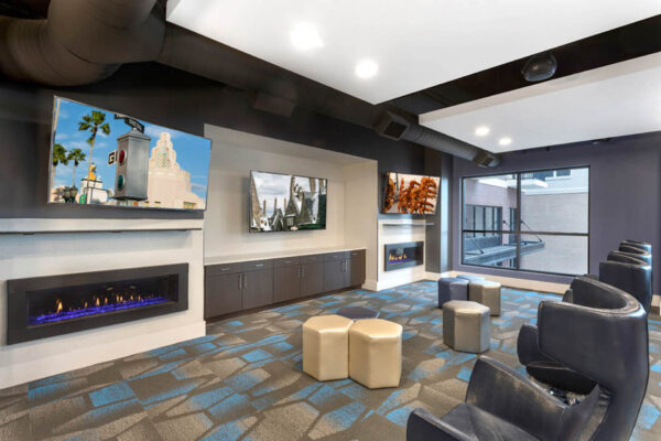 Forum Fitzsimons apartments lounge with plush seating, fireplace, and TVs.