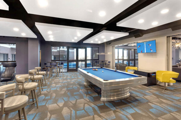 Forum Fitzsimons apartments lounge with pool table, arcade game, and TV.
