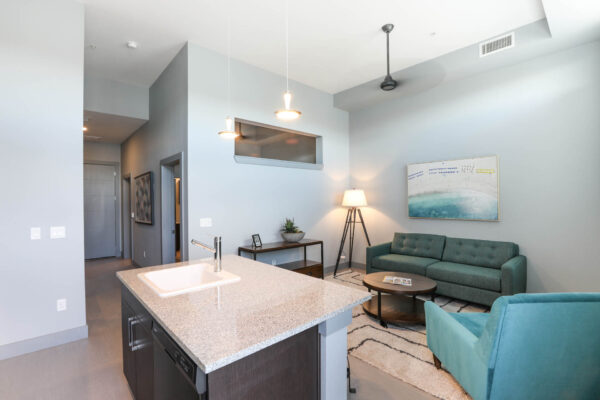 Forum Fitzsimons apartment living room with plush seating, ceiling fan, and cool gray walls.