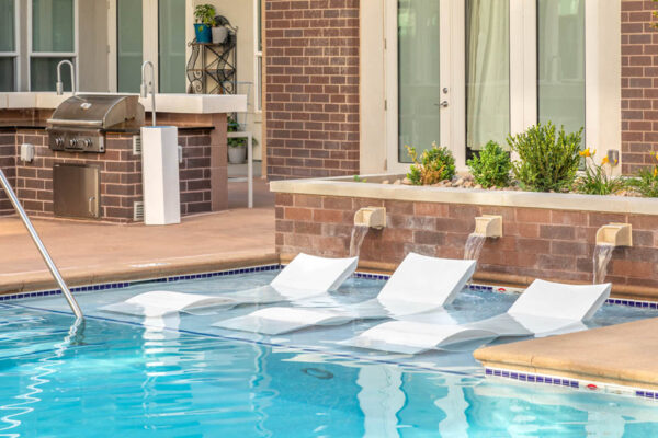 Forum Fitzsimons apartments pool area with lounge chairs and BBQ grills.