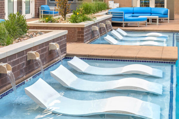 Forum Fitzsimons apartments pool area with lounge chairs and fountains.