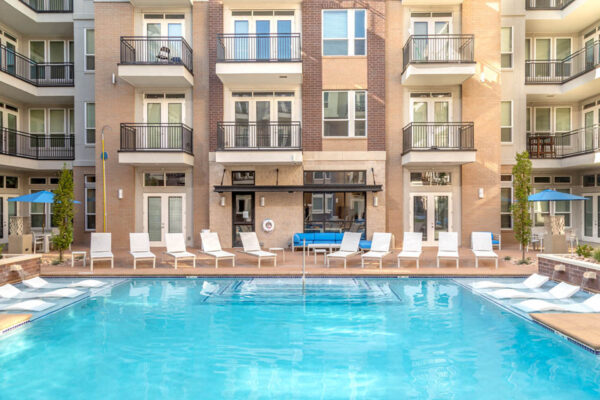 Forum Fitzsimons apartments pool area with lounge chairs, outdoor couches, and umbrellas.