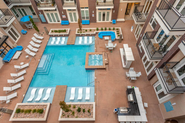 Forum Fitzsimons apartments pool area with lounge chairs, hot tub, and BBQ grills.