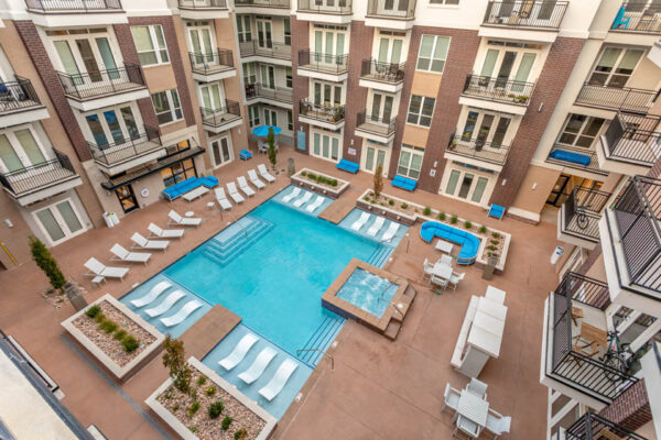 Forum Fitzsimons apartments pool area with lounge chairs, hot tub, and fireplace.