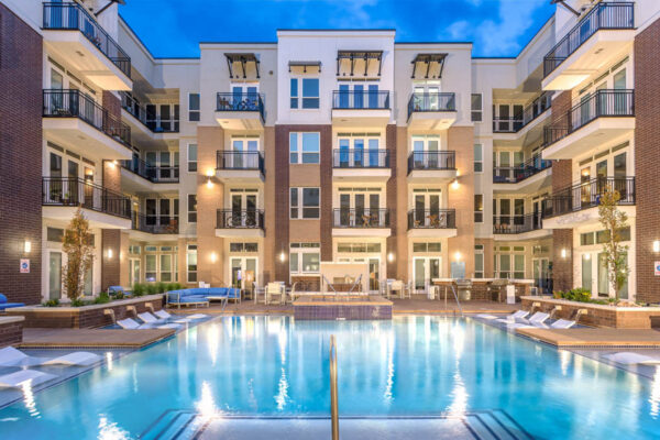 Forum Fitzsimons apartments pool area at dusk with lounge chairs and hot tub.