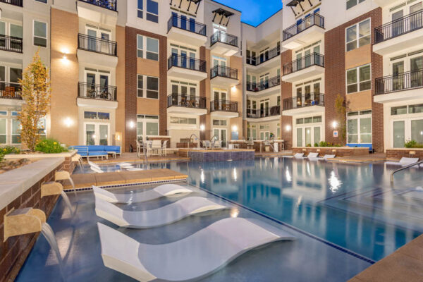 Forum Fitzsimons apartments pool area at dusk with lounge chairs and hot tub.