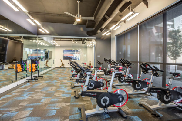 Forum Fitzsimons apartments fitness center with cardio machines and TV.