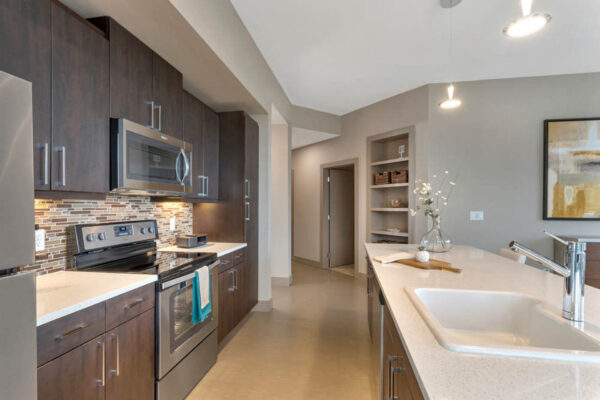 Forum Fitzsimons apartment kitchen with dark cabinets, light counters, and stainless steel appliances.