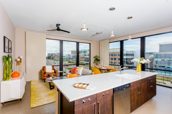 Forum Fitzsimons apartment living area with breakfast bar, plush seating, elegant dining, and large windows.