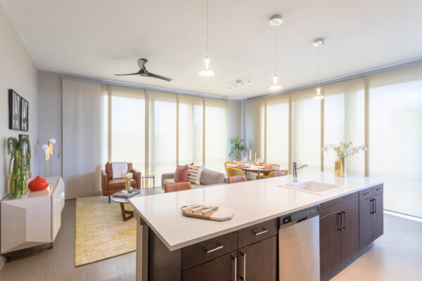Forum Fitzsimons apartment living area with breakfast bar, plush seating, elegant dining, and large windows.