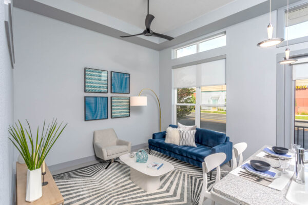 Forum Fitzsimons apartment living room with pattern rug, plush seating, framed art, and large windows.