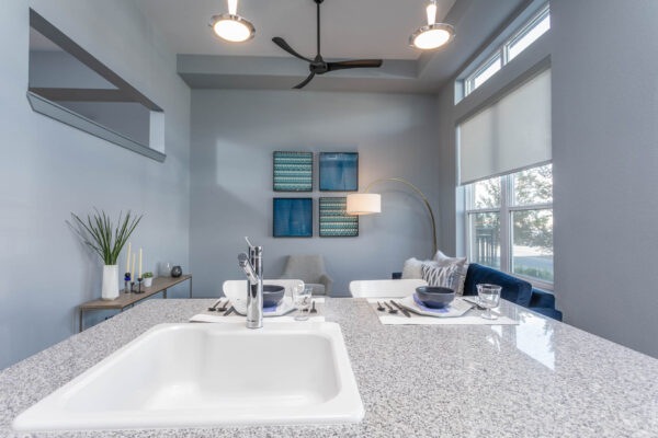 Forum Fitzsimons apartment living area with breakfast bar, plush seating area, and large windows.