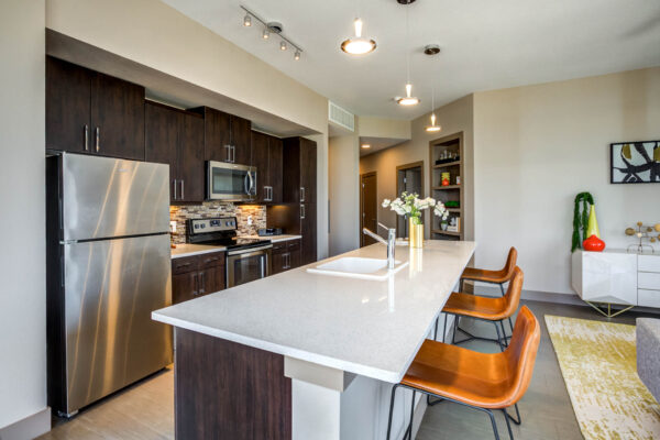 Forum Fitzsimons apartment kitchen with dark cabinets, light counters, and stainless steel appliances.