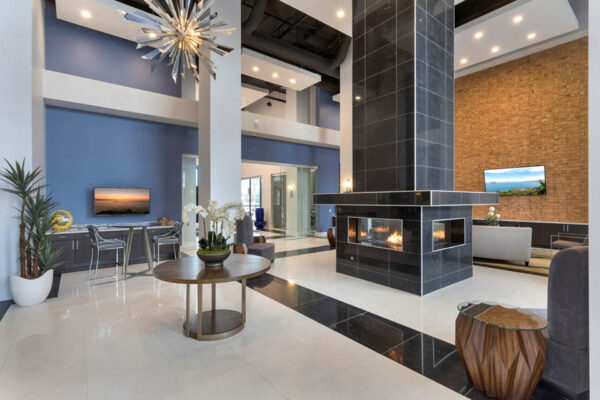Forum Fitzsimons apartment lobby with tables, TV, and fireplace.