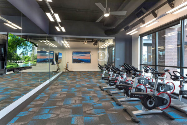 Forum Fitzsimons apartments fitness center with spin bikes and mirror walls.