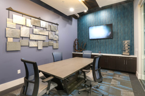 Forum Fitzsimons apartment business center with conference table and TV.