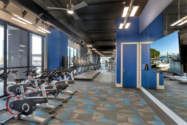 Forum Fitzsimons apartments fitness center with cardio machines and mirror wall.