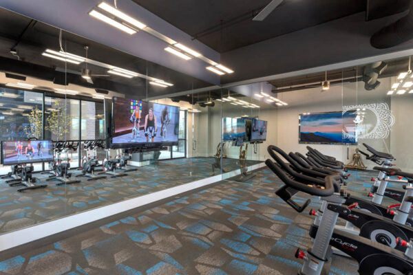 Forum Fitzsimons apartments fitness center with cardio machines and mirror wall.