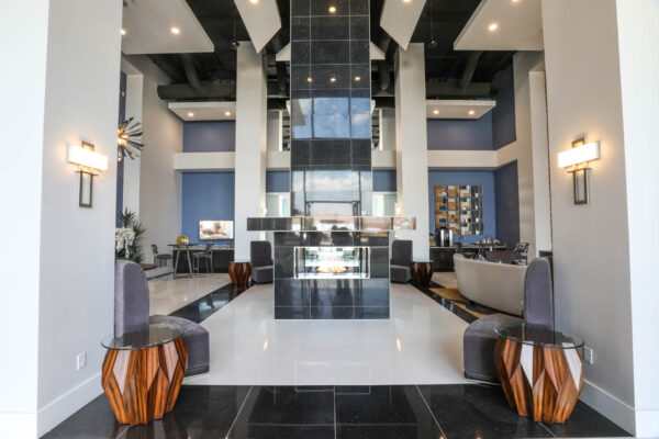 Forum Fitzsimons apartment clubroom with shiny black tiled fireplace and plush seating.