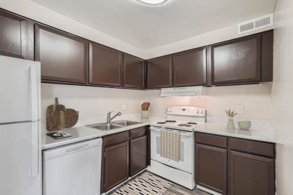 Heights on Huron apartments kitchen with wood style floors, wood cabinets, light counters and white appliances.