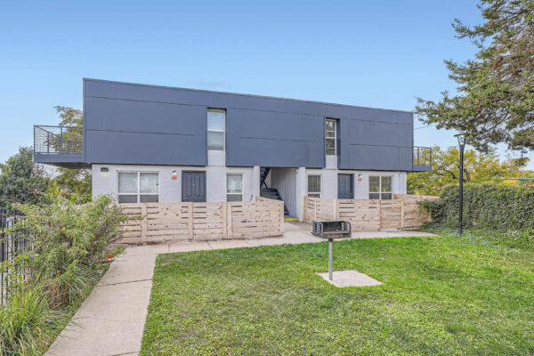 Heights on Huron apartments building with fenced entryway, central staircase and grassy area with BBQ grill.
