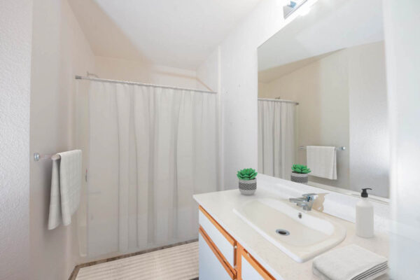 Mountain Village apartments bathroom with with white cabinets and large mirror.