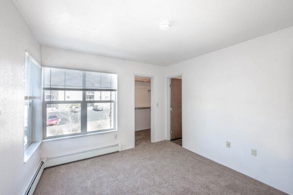 Mountain Village apartments bedroom area with plush carpet, large windows and closet.