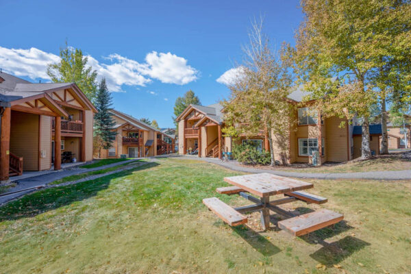 Mountain Village apartments buildings with picnic table in grassy area.