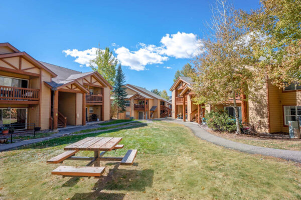 Mountain Village apartments buildings with picnic table in grassy area.