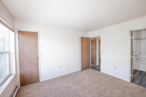 Mountain Village apartments bedroom area with large window, wooden doors and modern bathroom.