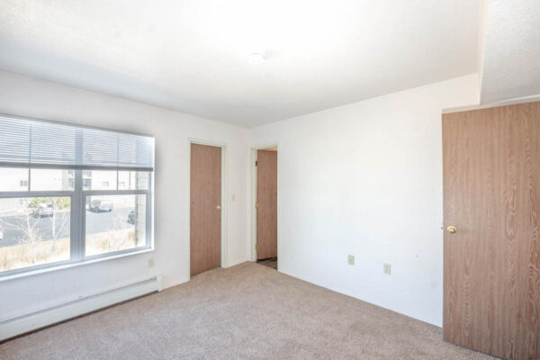 Mountain Village apartments bedroom area with plush carpet, large windows and wooden doors.