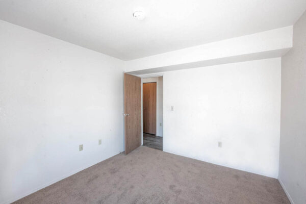 Mountain Village apartments bedroom area with plush carpet and wooden door.