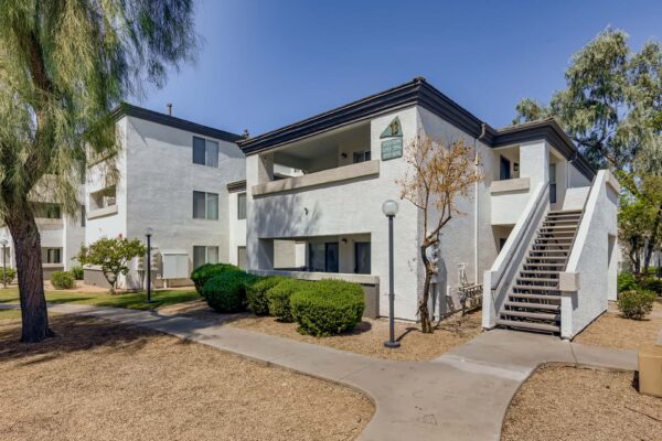Pavilions at Arrowhead apartments with simple architecture, rocky landscaping, and tall trees.