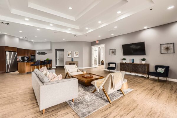 Pavilions at Arrowhead apartments community lounge with plush seating, TV, and community kitchen.
