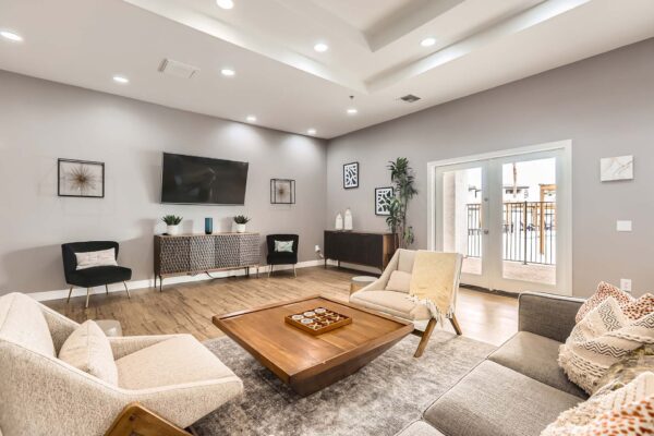 Pavilions at Arrowhead apartments community lounge with plush seating and door to pool area.