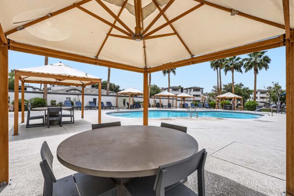 Pavilions at Arrowhead apartments pool area with lounge chairs and gazebos.