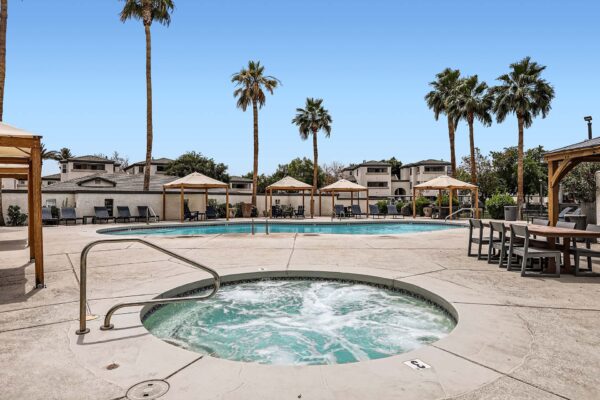 Pavilions at Arrowhead apartments pool area with hot tub and dining tables.