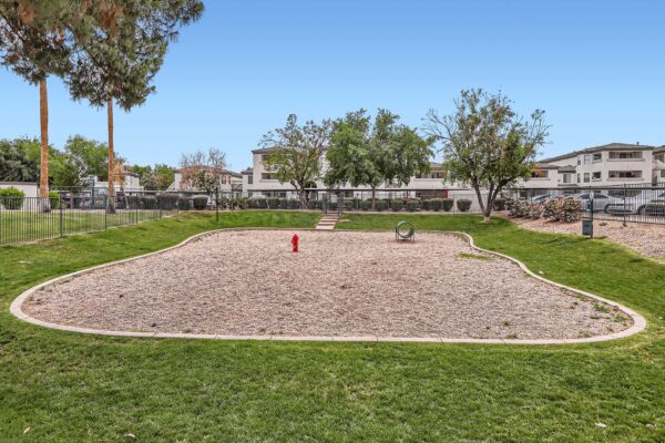 Pavilions at Arrowhead apartments dog park with agility toys and gravel play area.