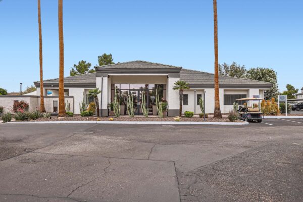 Pavilions at Arrowhead apartments clubhouse with rocky landscaping and tall palm trees.