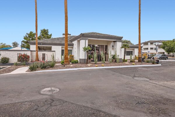 Pavilions at Arrowhead apartments clubhouse with rocky landscaping and tall palm trees.