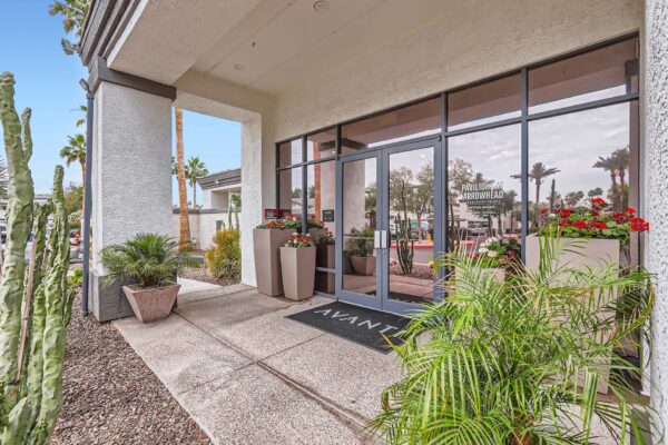 Pavilions at Arrowhead apartments clubhouse entrance with lush plants and flowers.