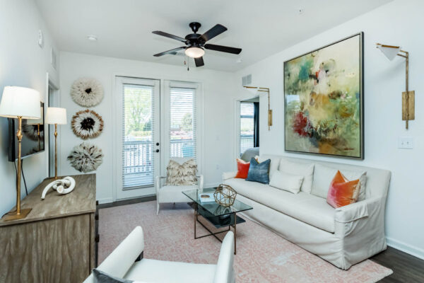 Residence at Old Hickory Lake apartments living area with wood style flooring, light fixtures, abstract artwork, ceiling fan and comfortable seating.