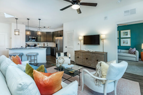 Residence at Old Hickory Lake apartments living area and modern kitchen with wood style flooring, light fixtures, abstract artwork, ceiling fan and comfortable seating.