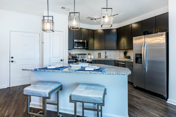 Residence at Old Hickory Lake apartments kitchen with dark style cabinets, stainless steel appliances, light fixtures, tiled backsplash and counters.