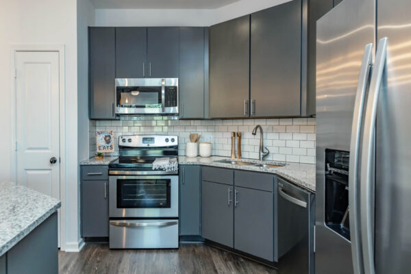 Residence at Old Hickory Lake apartments kitchen with dark style cabinets, stainless steel appliances, tiled backsplash and counters.