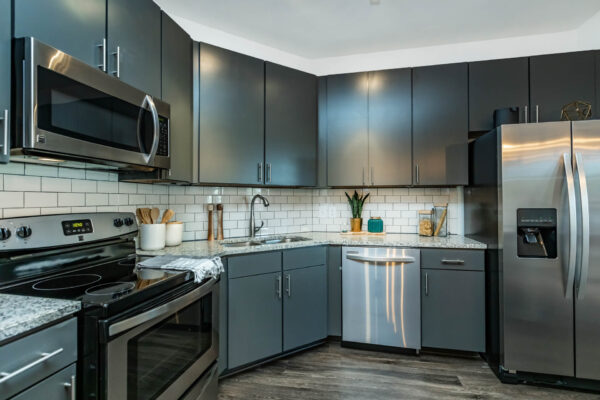 Residence at Old Hickory Lake apartments kitchen with dark style cabinets, stainless steel appliances, tiled backsplash and counters.