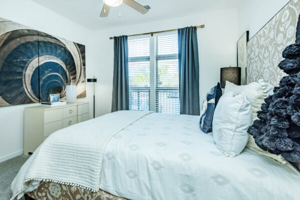 Residence at Old Hickory Lake apartments bedroom with dark style nightstands, large window, ceiling fan and abstract artwork.
