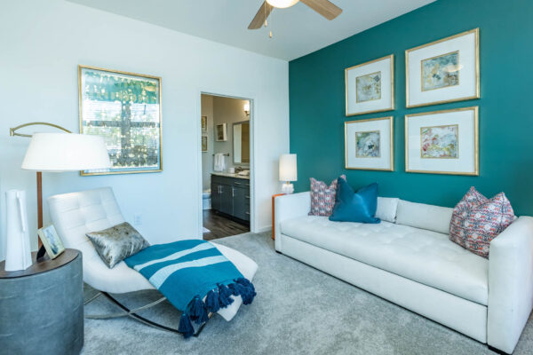 Residence at Old Hickory Lake apartments green painted walls, abstract artwork, and comfortable seating on plush carpet and ceiling fan.