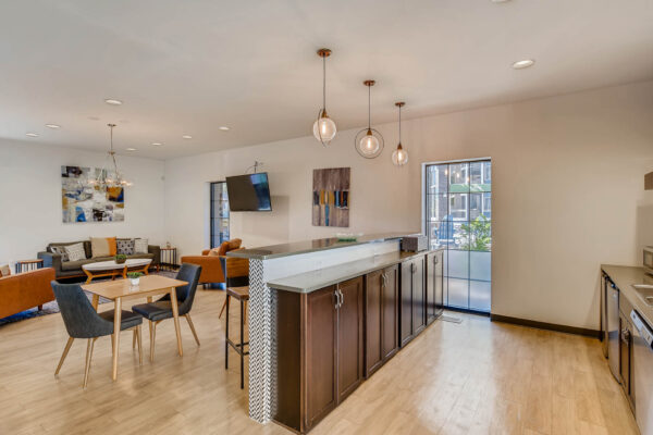 Sky at Bear Creek apartments community kitchen and lounge with tables and chairs, barstools, and tv