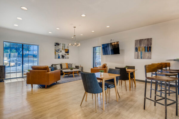 Sky at Bear Creek apartments community kitchen and lounge with tables and chairs, barstools, and tv